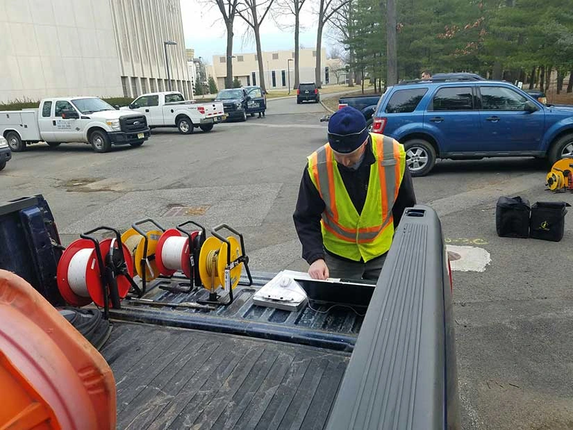 Man checking data on computer standing at back of truck