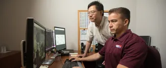 2 men reviewing 3 computer screens. site map plotting