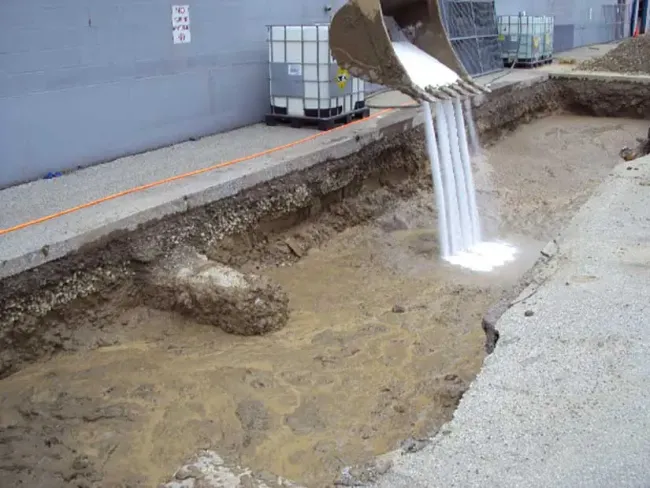 Excavator pouring into ditch