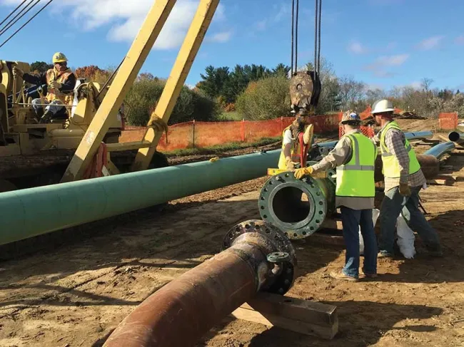 Workers standing by big pipes